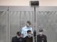 Ильназ Галявиев в аквариуме вместе с тремя полицейскими во время заседания суда. Фото: Наталия Колесникова / AFP