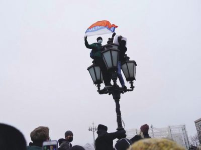 Два человека на фонаре во время митинга. Один с плакатом "Один за всех и все за одного", другой с флагом России и словом "Владивосток". Фото: Наталья Буданцева / ОВД-инфо"
